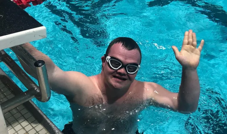 Middleboro YMCA swimmer CJ Roy waves in the pool at the Massachusetts Special Olympics.